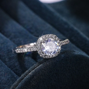 Macro shot of a halo diamond ring with round center stone and pavé band on velvet