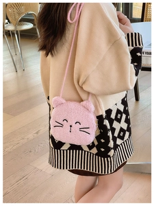 Pink plush cat crossbody bag with embroidered details worn over the shoulder by a model