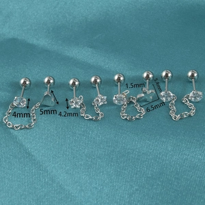 Stainless steel chain earrings with cubic zirconia heart and star pendants on blue fabric