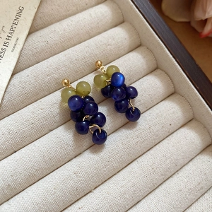 Detailed macro view of the resin grape cluster earrings in dark blue and green beads