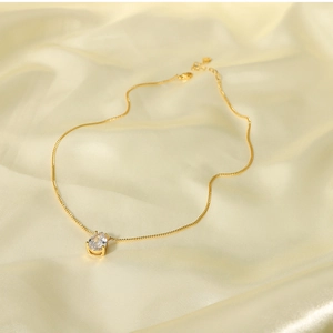 Detailed view of 18k gold plated teardrop white zircon pendant on delicate link chain