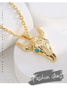 Macro detail of golden bull head pendant with blue gemstones and floral engraving