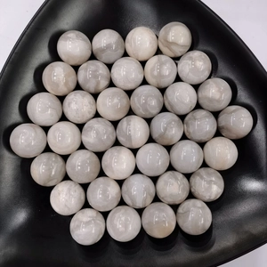 Top-down view of smooth 25mm natural white quartz crystal spheres in a black tray