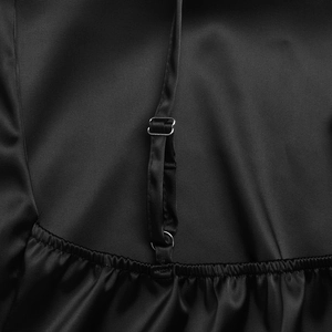 Close-up of adjustable spaghetti strap and pleated satin fabric on a black evening dress