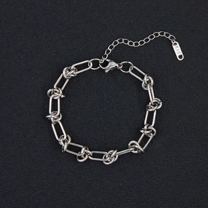 Macro detail of silver stainless steel twisted link bracelet with K18 tag and lobster clasp