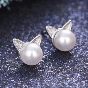 Close-up of cat-ear pearl stud earrings with sparkling silver texture and white pearls