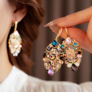 Macro detail of vintage floral teardrop earrings with multi-color crystals and gold base