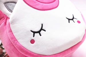 Close-up of pink unicorn plush backpack showing soft texture and embroidered eyelashes