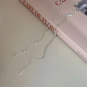 Detail of layered S925 sterling silver beaded and Figaro chains on a French cafe book