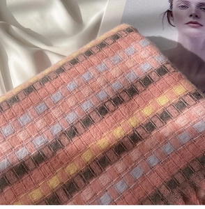 Close-up of soft rainbow plaid knit scarf texture with delicate tassels and fringe detail