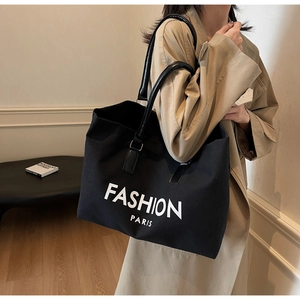 Große schwarze Canvas-Tasche mit Fashion-Paris-Print getragen zum beigen Trenchcoat
