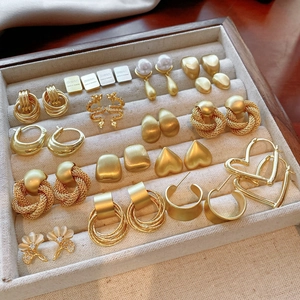 Selection of golden geometric earrings with pearls and rhinestones in a velvet tray