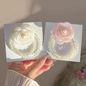 Close-up of white and pink camellia flower hair ties with elegant pearl bead strands