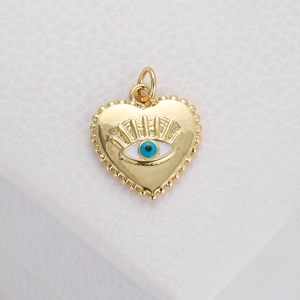 Macro detail of a golden heart evil eye pendant with blue and white enamel inlay
