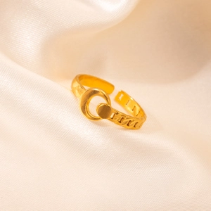 Close-up of golden adjustable open ring with chain texture on beige silk fabric