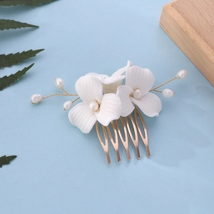Detail of elegant white ceramic magnolia flower and pearl bridal hair comb pins
