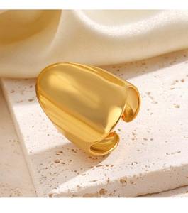 Gros plan sur une bague large en acier inoxydable doré sur pierre texturée et fond de soie