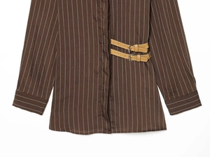 Close-up of brown striped shirt featuring decorative side faux leather buckles and texture