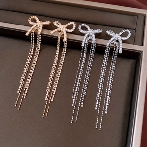 Close-up of gold and silver bow tassel earrings with sparkling rhinestones in a gift box