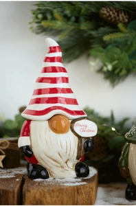 Detail of Santa gnome ceramic jar with Merry Christmas sign on snow-covered wood