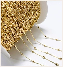 Close-up of golden beaded metal chain on a spool for DIY jewelry making supplies