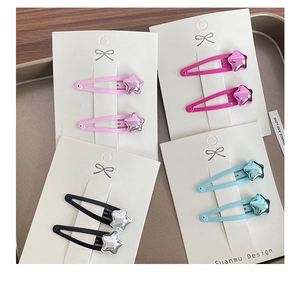Detail of metallic star hair clips in pink, black, and blue on display cardboards