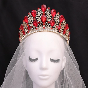 Detailed close-up of a luxury gold baroque crown with large red waterdrop crystals and rhinestones