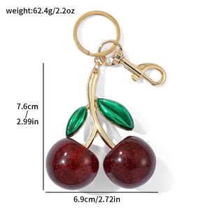 Detail showing red cherry keychain with gold hardware and dimensions 7.6cm by 6.9cm