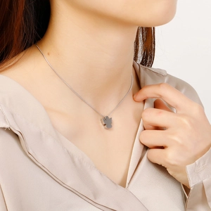 Detail shot of a silver angel pendant necklace worn by a model for size and style reference