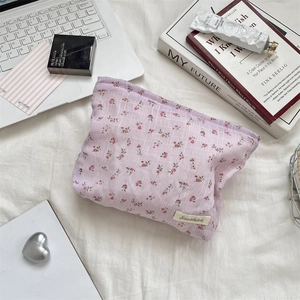 Détails d'une trousse de toilette lilas à fleurs avec cosmétiques sur une table blanche