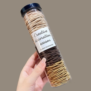 Detail von hochelastischen Haargummis im transparenten Zylinder in Beige- und Brauntönen