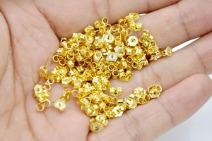 Close-up of butterfly earring backs in 18K gold plated copper held in a person's palm
