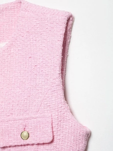 Détail du gilet en tweed rose montrant la texture tissée et le bouton en métal doré
