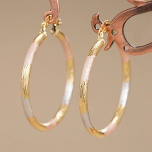 Three-tone wavy hoop earrings in gold, silver, and pink with a sleek metal finish