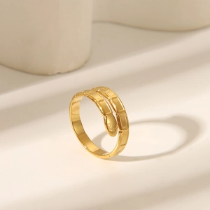 Detailed view of a gold-plated snake ring on a stone pedestal under soft natural light