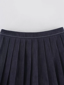 Dettaglio della gonna a pieghe in denim blu scuro con cuciture bianche in vita