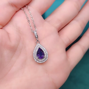Macro shot of silver teardrop pendant with pear-shaped purple stone and diamond halo