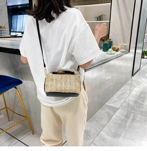 Detail of woven straw crossbody bag with black leather base shown on a model