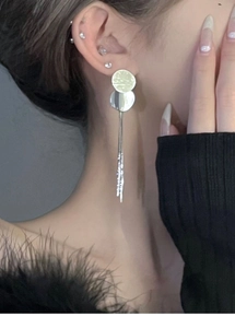 Detail view of silver sequin tassel earrings worn by a model for a stylish metal look
