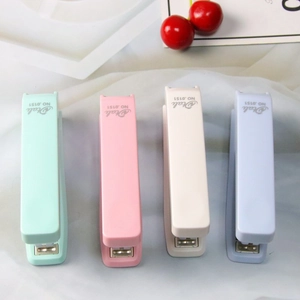 Overhead view of four pastel Morandi staplers arranged on a white textured fabric background