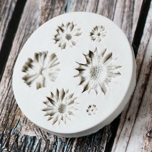 Detailed view of white silicone mold featuring six daisy sunflower patterns on wood background