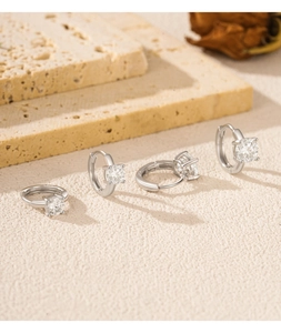 Détail de boucles d'oreilles créoles en moissanite argentée sur support en pierre beige