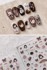 Detail of embossed nail stickers featuring cute girl, bear, and bow motifs in brown tones