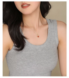 Close-up of a red heart-shaped lock pendant necklace on model neck with gold chain