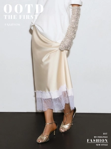 Detail of champagne satin skirt featuring delicate white lace trim and smooth fabric