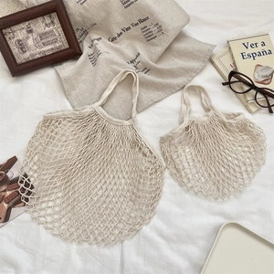 Détails des sacs filet en coton beige en deux tailles sur un fond en tissu blanc doux