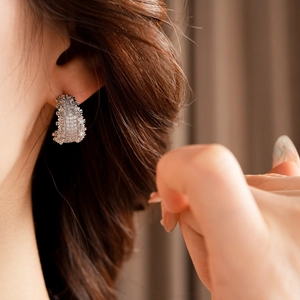 Gros plan détaillé de boucles d'oreilles argentées en C avec zircons sur un mannequin
