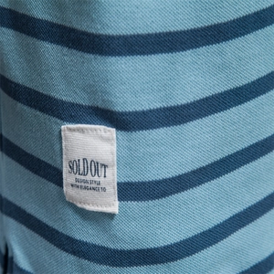 Macro detail of blue striped polo shirt fabric with a woven label and piqué cotton texture