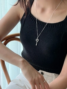 Minimalist silver key pendant necklace worn by a model in casual lifestyle setting