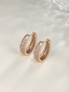 Close-up of rose gold geometric earrings featuring rows of brilliant white zircon pavé